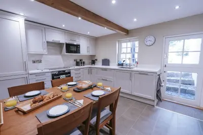 a kitchen with a wooden table and a dining room at Bluck's cottage in St. Agnes