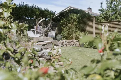 a garden with a statue in the middle of a yard at Bluck's cottage in St. Agnes