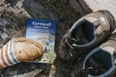 a persons foot next to a shoe and a book at Bluck's cottage in St. Agnes