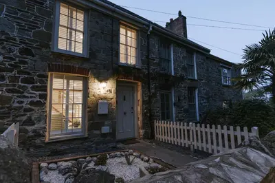 a stone house with a white fence in front of it at Bluck's cottage in St. Agnes