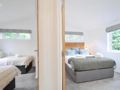 a bedroom with two beds and a mirror at 3 Meadow Retreat in Liskeard