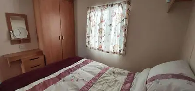 a small bedroom with a bed and a window at 5Berth -Family Friendly -ParkingSpot -Heated Pool in St Austell