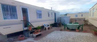 an rv with a table and chairs in a yard at 5Berth -Family Friendly -ParkingSpot -Heated Pool in St Austell