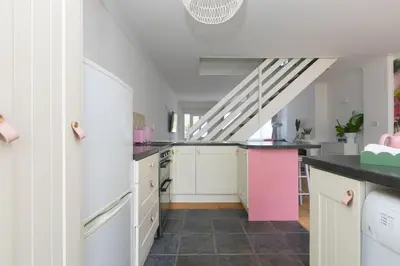 a kitchen with white cabinets and a pink island at Pebble in Carbis Bay