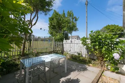 a table and chairs in a backyard with a fence at Pebble in Carbis Bay