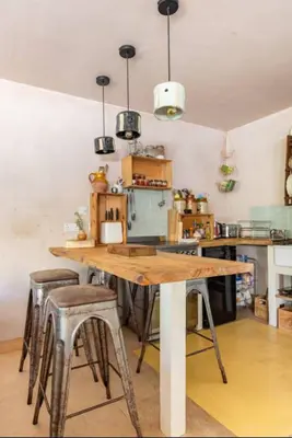 a kitchen with a wooden table and stools at The Birch House in Saint Columb Major