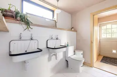 a bathroom with a toilet and a sink and a window at The Birch House in Saint Columb Major