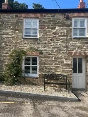 a bench sitting in front of a stone building at Honeysuckle Cottage in St. Agnes