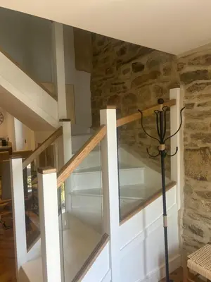 a glass staircase in a house with a stone wall at Honeysuckle Cottage in St. Agnes