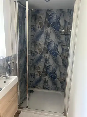 a shower with a glass door in a bathroom at Honeysuckle Cottage in St. Agnes