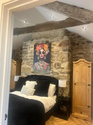 a bedroom with a stone wall with a bed at Honeysuckle Cottage in St. Agnes