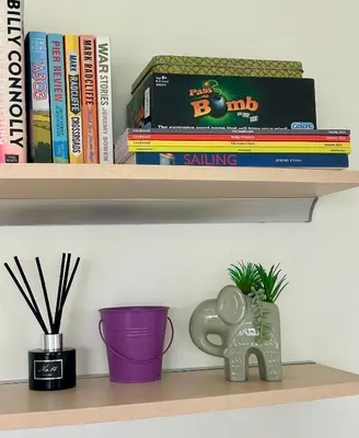 a shelf with books and a purple vase and books at 204 Atlantic Bays, St Merryn in St Merryn