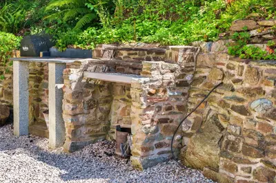 a stone wall with a table on top of it at Finest Retreats - The Old Vicarage in Talland