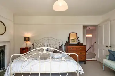 a bedroom with a white bed and a dresser and a mirror at Finest Retreats - The Old Vicarage in Talland