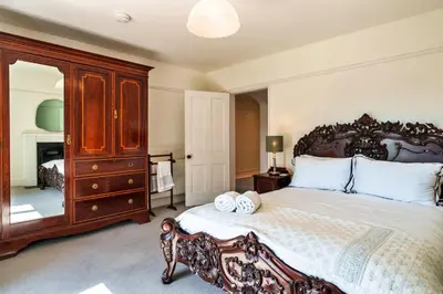 a bedroom with a large bed and a dresser at Finest Retreats - The Old Vicarage in Talland