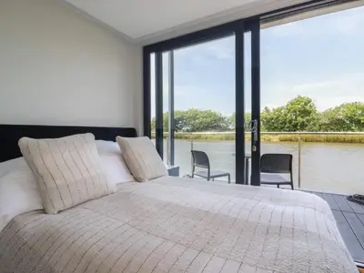 a bedroom with a large bed with a view of the water at Riverside Exclusive Retreat in Newquay