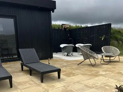 a patio with chairs and a table and a tub at Riverside Exclusive Retreat in Newquay