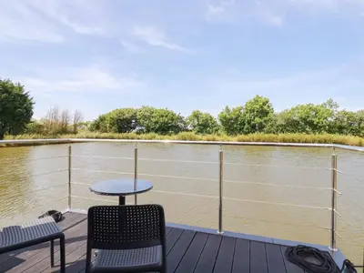 a deck with a table and chairs and a view of a river at Riverside Exclusive Retreat in Newquay