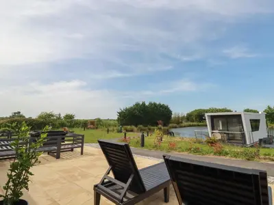 a group of chairs sitting on a patio near a river at Riverside Exclusive Retreat in Newquay