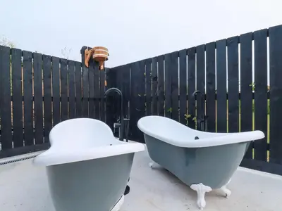 a white bath tub and a white toilet in front of a fence at Riverside Exclusive Retreat in Newquay