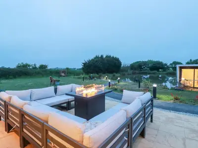 a patio with couches and a table and a pond at Riverside Exclusive Retreat in Newquay