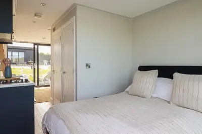 a bedroom with a bed and a kitchen at Riverside Exclusive Retreat in Newquay