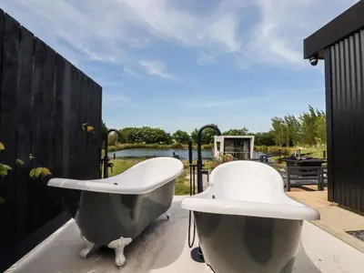 a bath tub and a chair sitting on a patio at Riverside Exclusive Retreat in Newquay