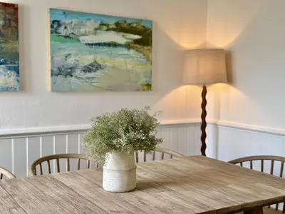 a table with a lamp and a vase with a plant on it at 1 Netherton in Padstow