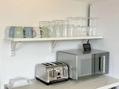 a kitchen with a toaster oven and glasses on shelves at 1 Netherton in Padstow