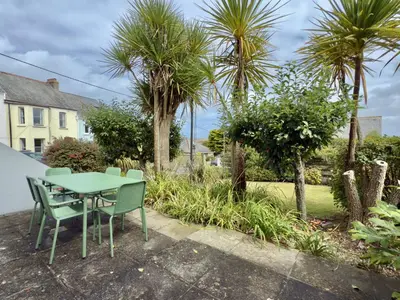 a table and chairs in a garden with palm trees at 1 Netherton in Padstow