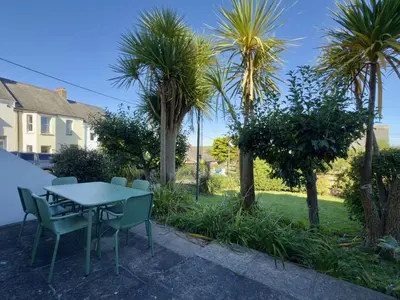 a patio with a table and chairs and palm trees at 1 Netherton in Padstow
