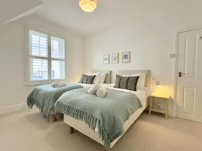 a white bedroom with two beds with towels on them at 1 Netherton in Padstow
