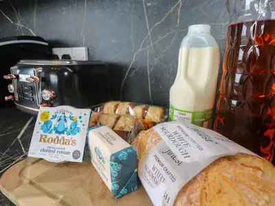 a cutting board with bread and a bottle of milk at St Marys in Penzance