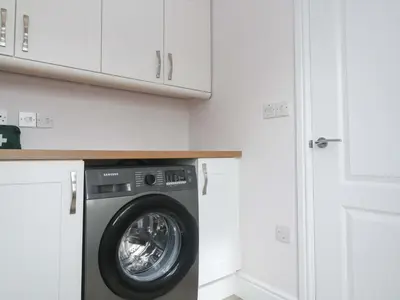 a washing machine in a kitchen with white cabinets at St Marys in Penzance