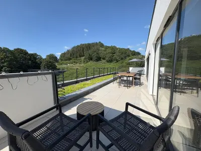 a balcony with two chairs and a table and tables at Skyfall in Downderry