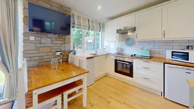 a kitchen with white cabinets and a stone wall at St Ives Kornel Hewel 2 Bedrooms in St Ives