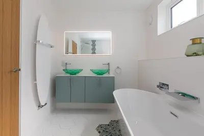 a bathroom with a tub and a sink and a mirror at Mor Glas in Carbis Bay