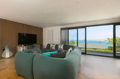 a living room with a blue couch and a television at Mor Glas in Carbis Bay