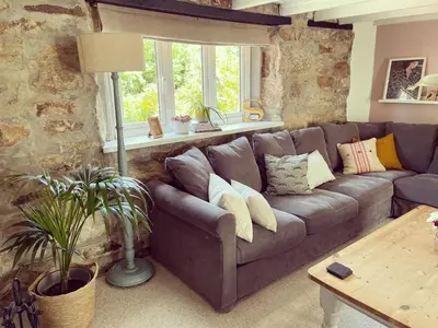 a living room with a couch and a window at April Cottage in Saint Erth