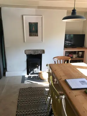 a living room with a table and a fireplace at April Cottage in Saint Erth