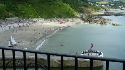 a beach with a bunch of people in the water at 9 Rock Towers in Looe