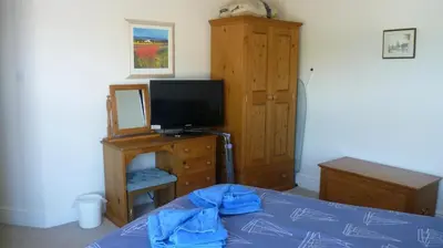 a bedroom with a bed and a tv and a dresser at 9 Rock Towers in Looe