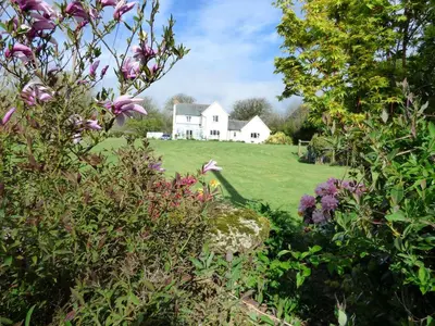 a white house on a green field with flowers at Copper Meadow in Launceston