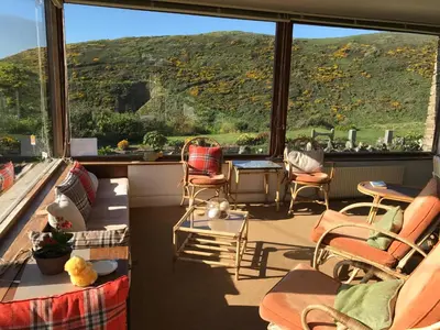 a living room with chairs and a large window at Cowrie, New Polzeath in Wadebridge