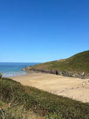 a beach with people walking on the sand at Cowrie, New Polzeath in Wadebridge