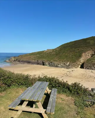 a picnic table sitting on top of a beach at Cowrie, New Polzeath in Wadebridge