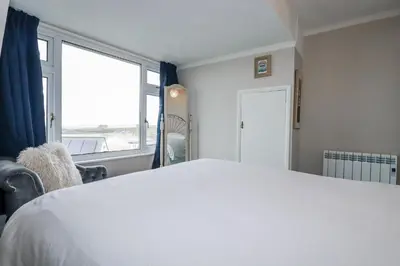 a bedroom with a white bed and a large window at Pipers in Newquay