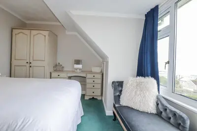 a bedroom with a bed and a chair and a window at Pipers in Newquay