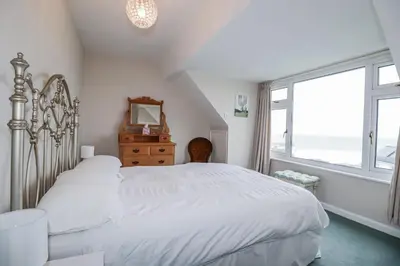 a bedroom with a white bed and a large window at Pipers in Newquay