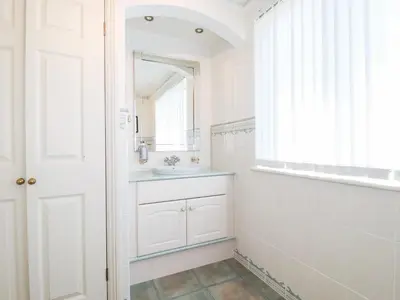 a white bathroom with a sink and a mirror at Pipers in Newquay